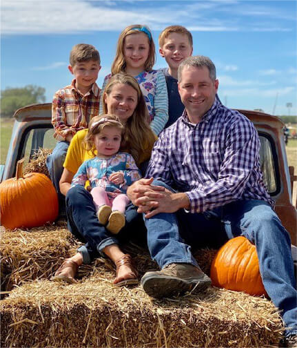 Mom and Dad and 3 kids with pumpkins in back of pick-up truck 